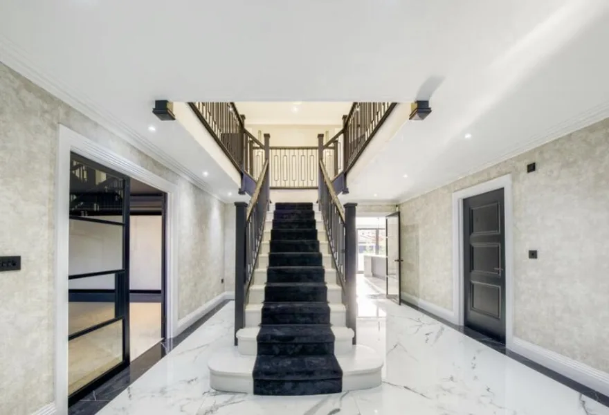 Entrance hall with a black staircase and marble floor