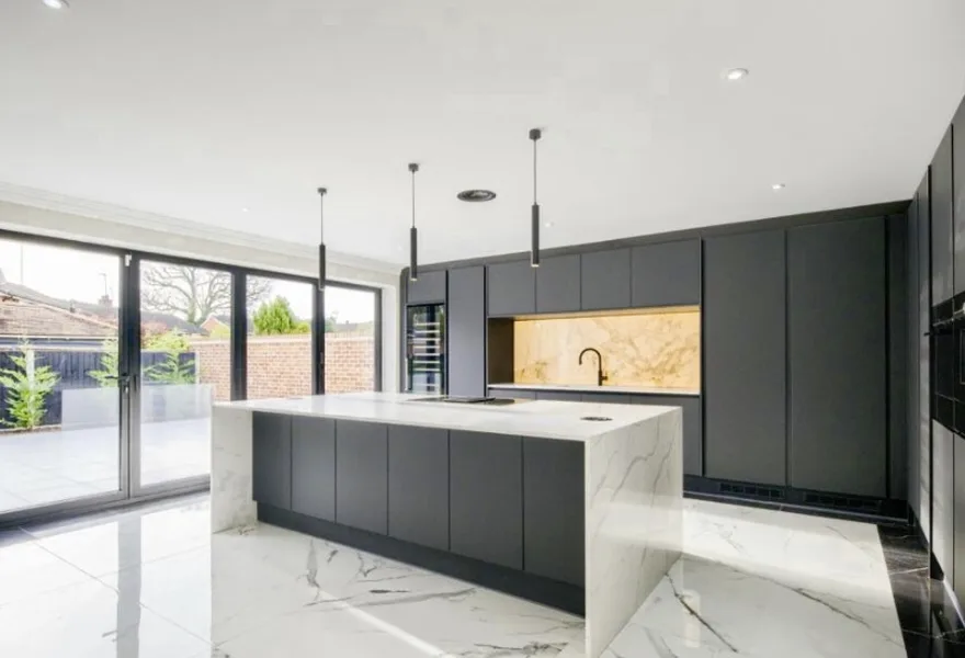Modern dark kitchen with a marble island and glass doors to the patio