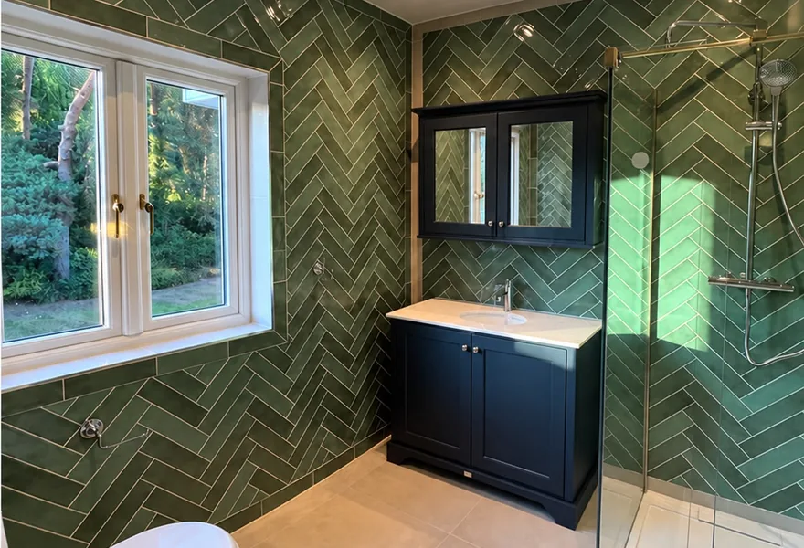 Renovated bathroom with green herringbone wall tiles, navy vanity unit and glass shower